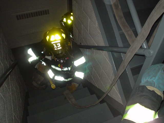 Members train on advacing a hose line up a staircase in a simulated smoke condition